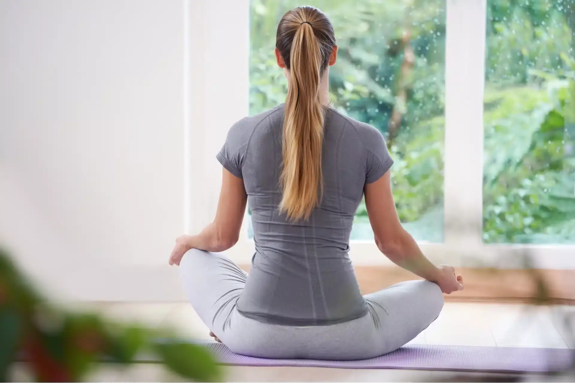 אישה יושבת בישיבה מזרחית עושה מדיטציה עם הגב אליינו