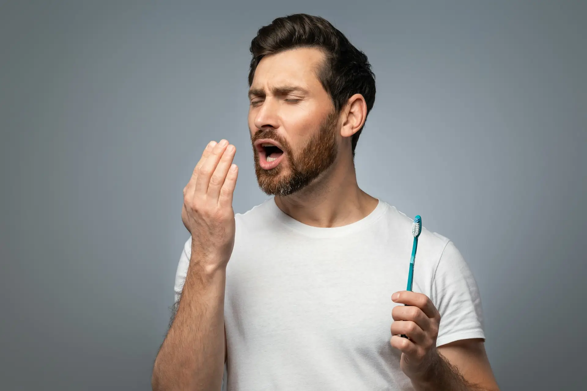 גבר אחרי צחצוח שיניים סובל מריח רע מהפה