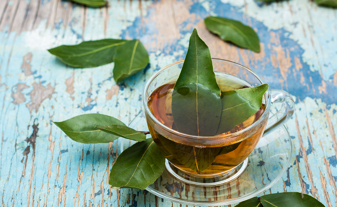 כוס תה עם עלי דפנה על שולחן עץ בצבע כחול