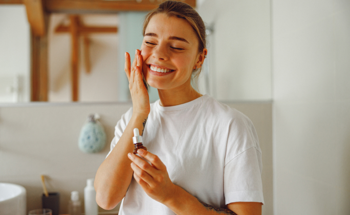 אישה מורחת שמן קצח על הפנים לטיפוח עור הפנים